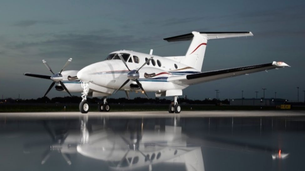 Turboprop aircraft positioned on a wet ramp at dusk